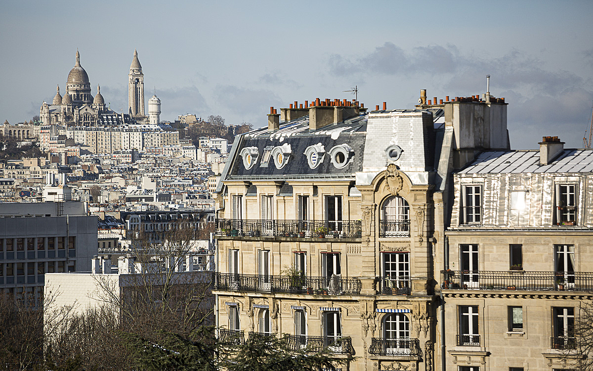 Vue d'un immeuble Haussmanien avec la butte Montmartre en fond