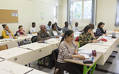 Des adultes assistent à des cours dans une salle de classe.