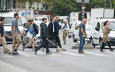 Piétons et personne malvoyante traversant sur un passage piéton