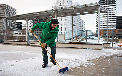 Un agent de la ville racle la neige au sol.