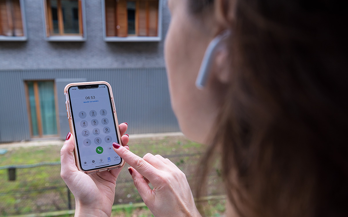 Une parisienne tient son téléphone portable dans la main et porte des oreillettes..