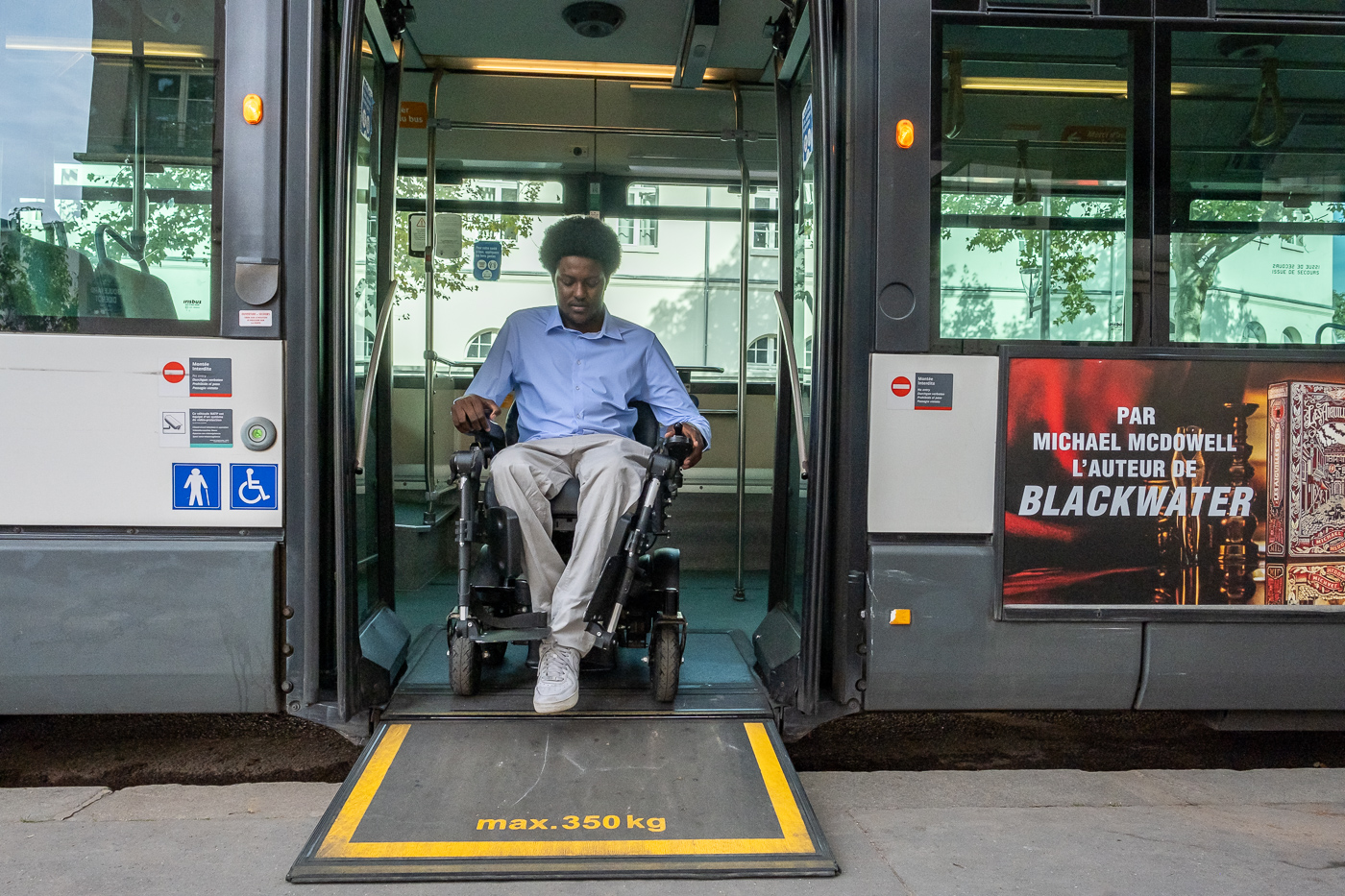 Personne en fauteuil roulant descendant d'un bus sur une rampe d'accès PMR