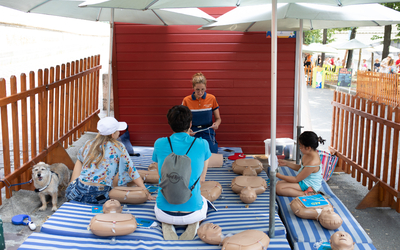 Une secouriste forme trois personnes aux gestes de secours.