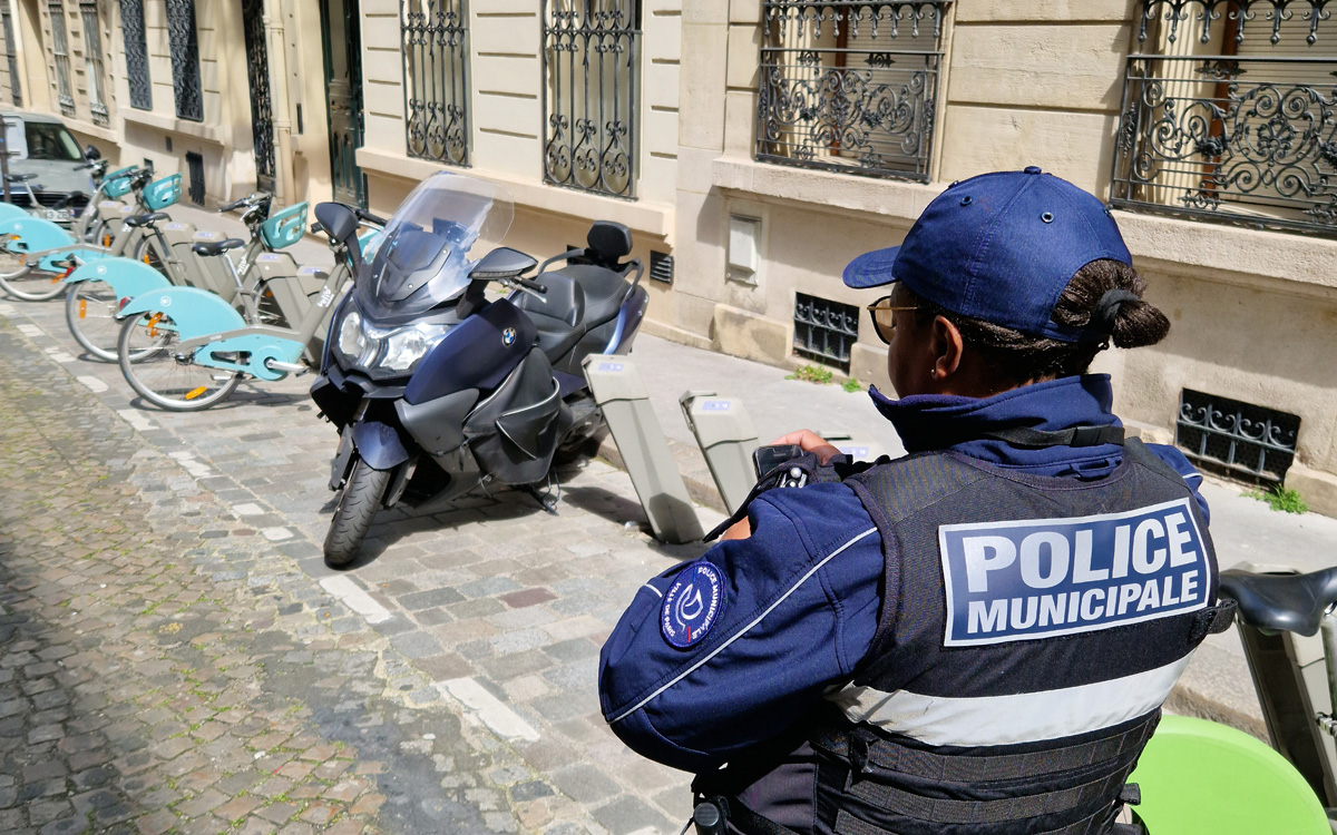 Un agent de Police Municipale verbalisant un scooter en stationnement gênant