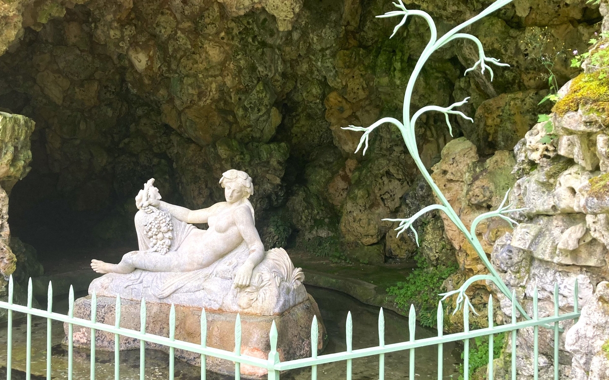 Statue en pierre d'une nymphe dans une grotte.