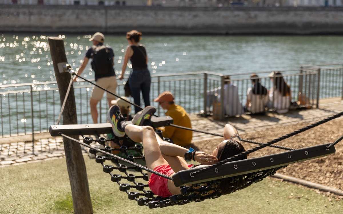 Une personne se repose dans un hamac sur les berges de Seine, rive droite.