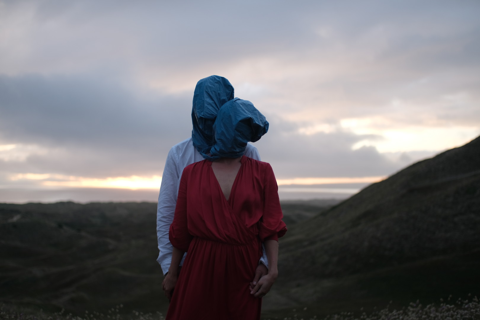 Deux personnes face à la caméra, leur visage caché par un sac plastique bleu.