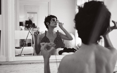 Une photographie en noir et blanc représentant l'actrice Audrey Tautou face à un miroir en train d'essayer des lunettes extravagantes
